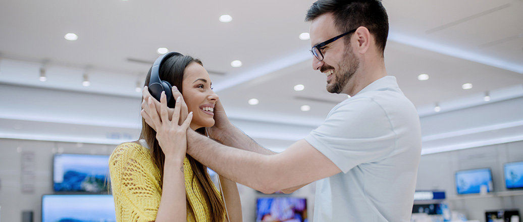 Young couple testing headphones in a tech store Young couple testing headphones in a tech store