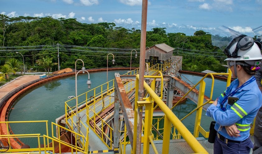 a woman wearing a helmet and standing on a bridge over a water basin