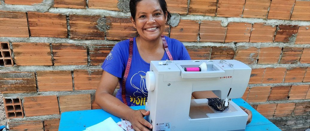 Costureira Angela Araújo sentada  com máquina de costura