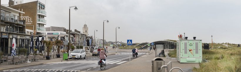 a person riding a bicycle on a road with buildings on either side a person riding a bicycle on a road with buildings on either side