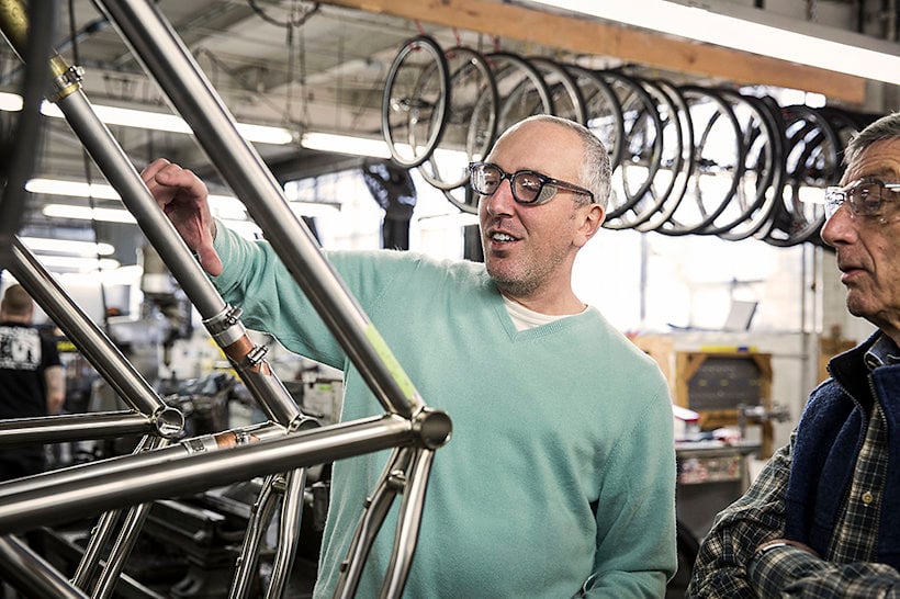 men in a bike shop, studying an aluminium frame